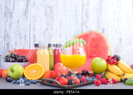 Jus en bouteilles, différentes et dans un verre. Un assortiment de fruits rouges et de fruits. Fond gris. L'alimentation de Detox. Copy space Banque D'Images