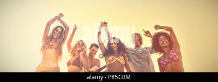 Groupe des amis de la danse à la plage pendant le coucher du soleil Banque D'Images