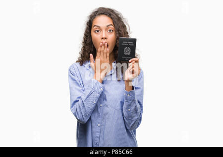 Young hispanic woman holding passport de l'Italie couvrir la bouche à part choqué avec honte pour erreur, expression de la peur, peur en silence, secret con Banque D'Images