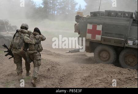 Soldat de l'Armée américaine du 2e Peloton, Comanche Troop, 1er Escadron, 2e régiment de cavalerie, Pologne Groupe de combat, aide à la simulation d'un soldat blessé à l'évacuation médicale au cours d'un combat d'entraînement dans le cadre de leur participation à la grève de sabre 18 ans au Bemowo Piskie Domaine de formation, la Pologne le 13 juin 2018, 13 juin 2018. Grève 18 Sabre est la huitième édition de l'armée américaine de longue date par l'Europe de la formation coopérative exercice visant à accroître l'interopérabilité entre les alliés et les partenaires régionaux. (Michigan Army National Guard photo de 1er lieutenant Erica Mitchell/ libéré). () Banque D'Images