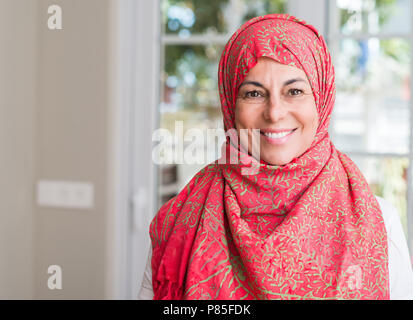 Middle aged femme musulmane portant le hijab avec un visage heureux et souriant debout avec un sourire confiant montrant les dents Banque D'Images