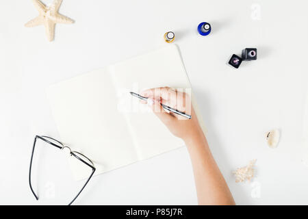 Mettre à plat la main de femme écrit dans un cahier. Vue de dessus de la table de travail des femmes Banque D'Images