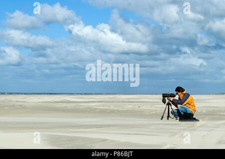 Vogelaar zittend op het strand rencontré telescoop ; observateur assis à plage avec telescope Banque D'Images