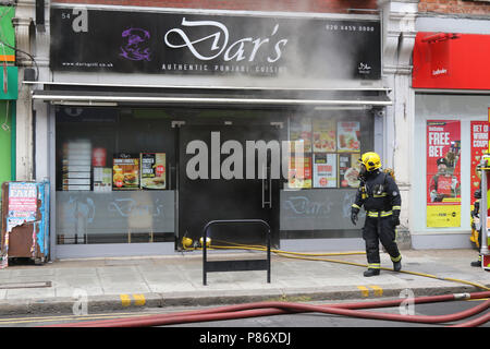 Londres, Royaume-Uni. 10 juillet 2018. Les pompiers luttant contre un incendie sur Willesden High Road tandis que la police armée avec des chiens renifleurs effectuer un raid et de procéder à des arrestations sur trois personnes, au nord-ouest de Londres le 10 juillet 2018 Crédit : Martin Evans/Alamy Live News Banque D'Images