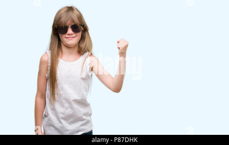 Jeune blonde toddler wearing sunglasses contrarié et frustré de crier avec colère, fou et hurlant de main levée, la colère concept Banque D'Images