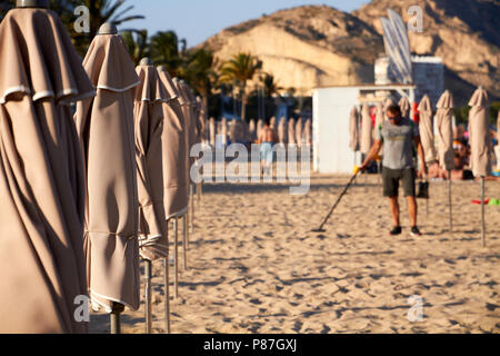 ALIACNTE, ESPAGNE, vers juillet 2018 hommes avec un détecteur de métal à la plage entre parasols Banque D'Images