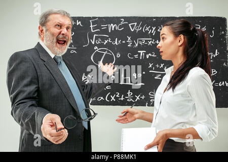 Le professeur masculin et jeune femme contre tableau in classroom Banque D'Images