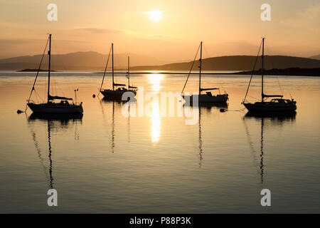 Coucher de soleil sur Ardmucknish à North Bay et l'aéroport Oban Connel avec voiliers en silhouette Banque D'Images