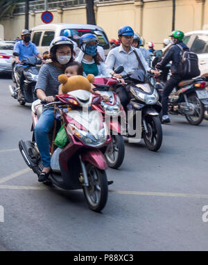 Les motocyclistes et les passagers avec des tout-petits ours équitation les motos dans la circulation à Ho Chi Minh City, Vietnam. Banque D'Images