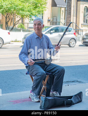 Personnes âgées chinese man joue un instrument traditionnel de Chine à une rue dans le quartier chinois de Toronto. Banque D'Images