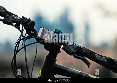 Guidon d'un vélo moderne, équipé d'un projecteur, d'une boussole et d'un déplacement et de leviers de frein et les fils. Fond urbain harmonieux. Banque D'Images