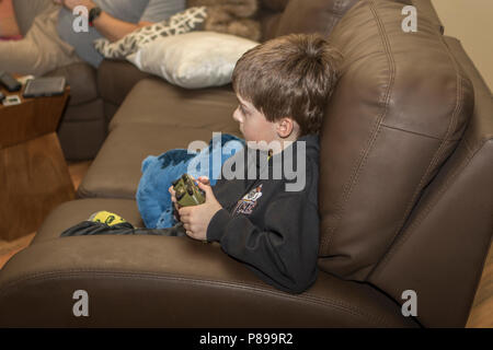 Jeune garçon, 10 ans, sur la table, avec tv vidéo contrôleur de jeu. Communiqué de modèle # 105. Banque D'Images