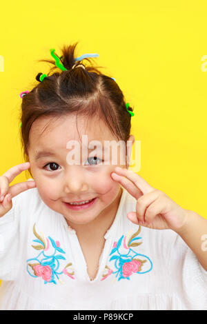 A quatre ans, petite fille asiatique grimaça à l'appareil photo Banque D'Images