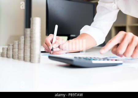 Des piles de pièces de comptabilité de l'entreprise avec le concept d'économiser de l'argent comptant, de prendre des notes de la calculatrice à la main, est écrit dans un cahier. Pièces empilées Banque D'Images