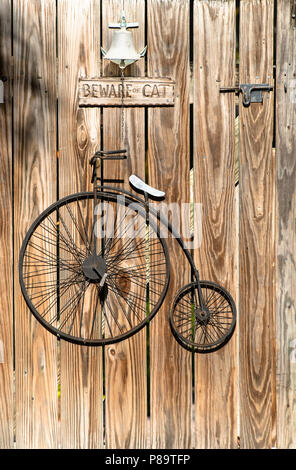 Roues de vélo à l'ancienne élevé, également appelé un Penny Farthing, décore d'une porte en bois porte dans Key West, Floride. Méfiez-vous de signer Cat est suspendu au-dessus. Banque D'Images