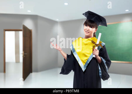 Happy asian woman avec graduation cap et faites défiler jusqu'à un diplôme à l'université Banque D'Images