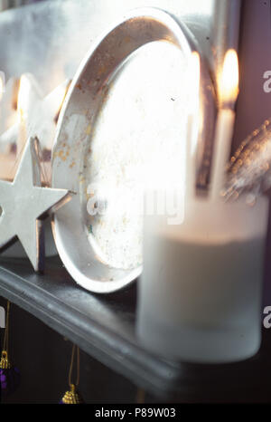 Close-up de cierge allumé dans un bocal en verre sur la tablette avec plaque métallique et l'argent l'étoile de Noël Banque D'Images