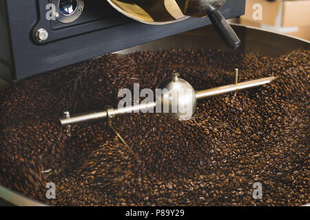 Les grains de café fraîchement torréfié provenant d'un grand torréfacteur de café dans le cylindre de refroidissement. Motion Blur sur les haricots Banque D'Images