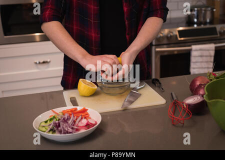 Woman squeezing lemon dans la cuisine Banque D'Images