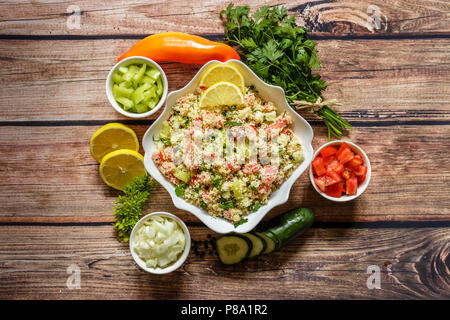 Des délicieux couscous aux légumes et fines herbes dans un bol en porcelaine blanche sur fond de bois, Close up Banque D'Images