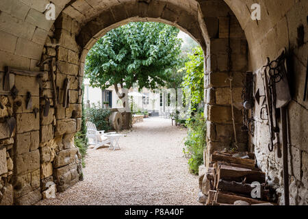 Arche de pierre de l'entrée est décoré de vieux outils agricoles laissés par les anciens propriétaires. Banque D'Images