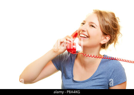 Happy young woman is phoning en poste fixe avec un récepteur téléphonique rouge Banque D'Images