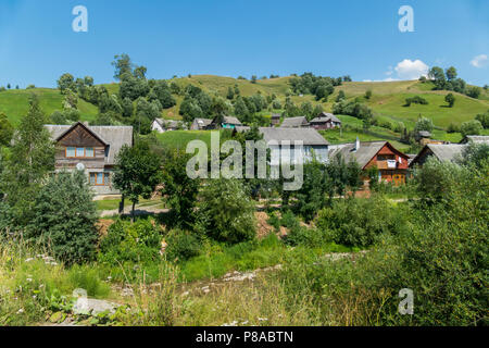 Un village avec des chalets de deux étages et de petites maisons sur le fond d'une montagne verte et un ciel bleu . Pour votre conception Banque D'Images