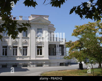 Un livre blanc hôtel particulier de deux étages, un domaine avec moulures en stuc, d''un balcon, d'arbres et d'une pelouse dans le contexte d'un creux, ciel sans nuages. Lieu de repos Banque D'Images