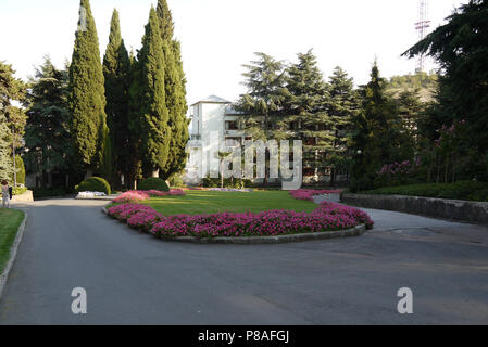 Une vue pittoresque d'un parterre de fleurs avec de belles fleurs dans un demi-cercle autour de plus en plus une pelouse verte. De l'article volé quelques arbres croissant près de th Banque D'Images