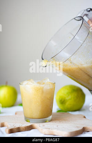 Smoothie aux fruits verts fraîchement mélangé dans un verre au fond nappe blanche. Blender, pomme verte, citron vert et menthe. Détox, régime alimentaire, manger propre wei Banque D'Images