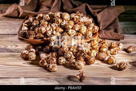 Maïs soufflé au caramel dans un bol en bois sur un fond de bois. Clé faible éclairage. Focus sélectif. Close-up Banque D'Images