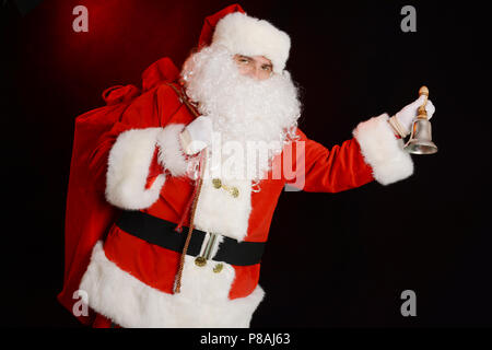 Traditionnel du Père Noël sonnerie sur une cloche, soins sac plein de présente Banque D'Images