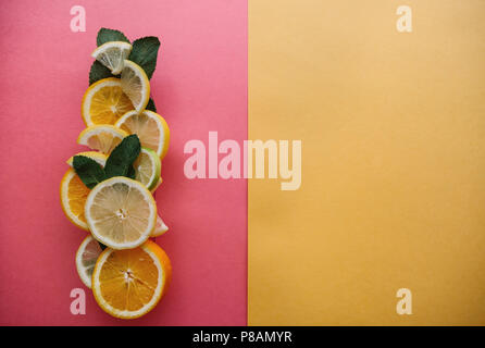 Les agrumes sur un fond coloré. De nombreuses tranches de citron, orange, citron vert et de feuilles de menthe se coucher ensemble. Beaucoup de fruits. Vitamines et une collation santé. Nearb Banque D'Images