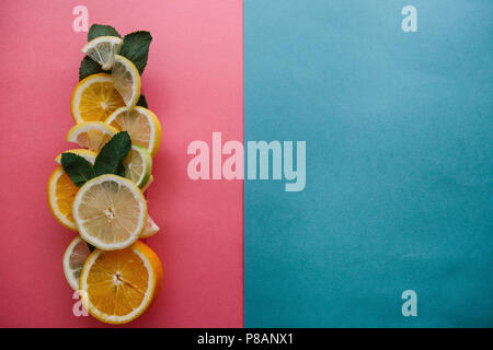 Les agrumes sur un fond coloré. De nombreuses tranches de citron, orange, citron vert et de feuilles de menthe se coucher ensemble. Beaucoup de fruits. Vitamines et une collation santé. Nearb Banque D'Images