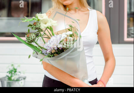 Jeune femme tenant un bouquet de fleurs délicates sur la rue près de flower shop Banque D'Images