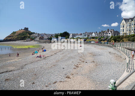 Plage de Criccieth et de vacances sur la péninsule de Lleyn dans le Nord du Pays de Galles avec les ruines du château de Criccieth dans l'arrière-plan Banque D'Images