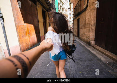 Vue arrière de la brunette holding anonyme de la personne et des cours en marchant sur la rue de Valence en Espagne Banque D'Images