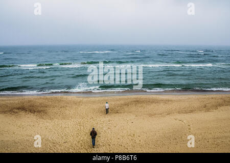 Vue arrière du couple en train de marcher sur le littoral et à la mer, à l'ondée de Courlande, Lituanie Banque D'Images