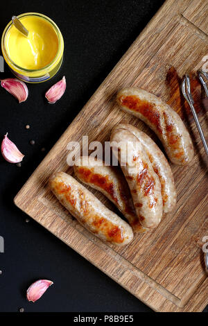 Petites grillades de saucisses allemandes reste sur une planche en bois servi avec de la moutarde Banque D'Images