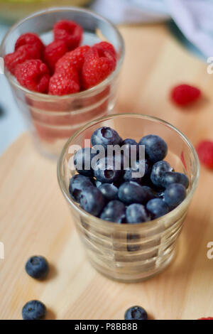 Saine alimentation végétalien végétarien savoureux petit-déjeuner détox avec fruits frais de saison et de baies servi sur planche à découper sur fond bleu pastel Banque D'Images