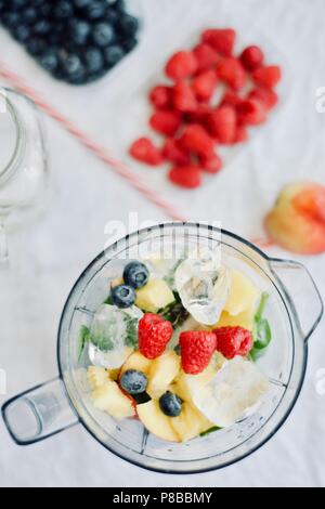 Télévision à jeter d'un mélangeur et petits fruits frais de saison et de fruits sur fond blanc, la cuisson la préparation des smoothies, Detox, saine alimentation propre Banque D'Images