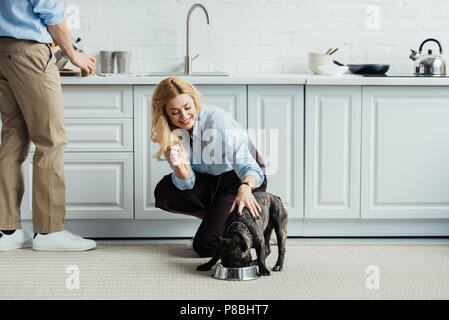 Le café de l'homme et femme blonde caresser bouledogue français sur plancher de la cuisine Banque D'Images