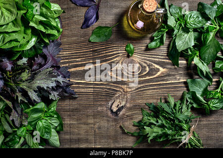 Variété d'herbes organiques fraîches sur fond de bois. Les herbes fraîchement récoltées y compris le basilic, roquette. Vue d'en haut. Copier l'espace. Banque D'Images