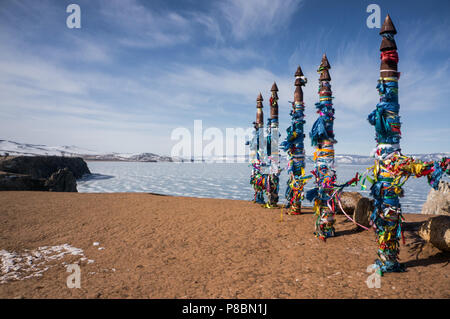 Piliers en bois avec des rubans colorés sur le littoral à la mer d'hiver Banque D'Images