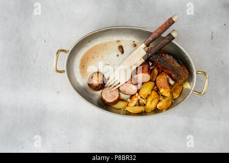 Vue de dessus avec des saucisses frites pommes de terre dans une poêle sur une surface d'éclairage Banque D'Images