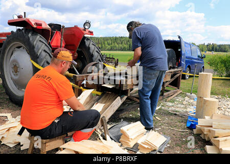 Deux charpentiers démontrer la compétence de faire des bardeaux de bois pour la toiture sur Kama & Mac Gregor, Traktorkavalkad Cavalcade du tracteur. Kama & Mac Gregor, Finlande - Juillet 7, 18. Banque D'Images