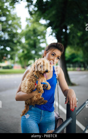 Portrait de la belle jeune femme avec son petit chiot caniche rouge. Banque D'Images