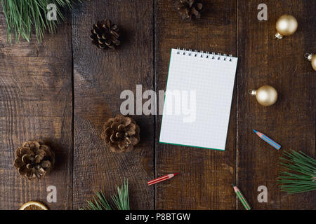 Fond de Noël avec petit carnet et des décorations de table en bois sombre, vue du dessus Banque D'Images