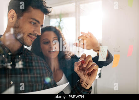 Man notes adhésives collées sur du verre transparent wall in office. Collègues de bureau d'affaires de discuter des idées et des plans sur un transparent Banque D'Images