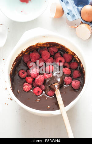 Framboises brownies au chocolat avec la pâte dans un bol blanc Banque D'Images